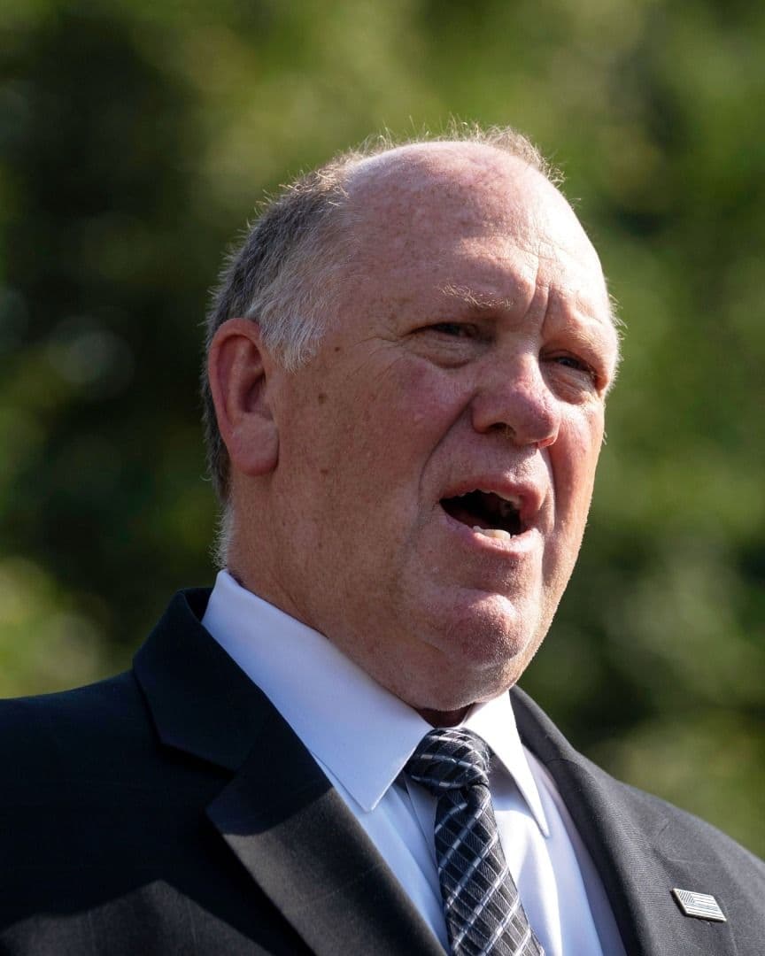 Tom Homan viste traje y corbata oscuros mientras habla