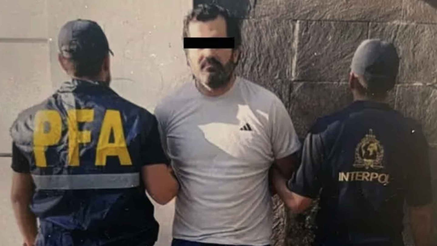 El contralmirante Fernando Farías Laguna con una camiseta blanca, aparece esposado y escoltado por dos agentes. En sus chalecos se lee "PFA" e "INTERPOL". Fue detenido en Argentina